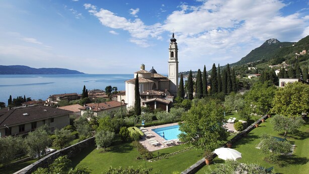 Eine Villa mit Swimmingpool, Garten und einer Kirche mit Glockenturm.