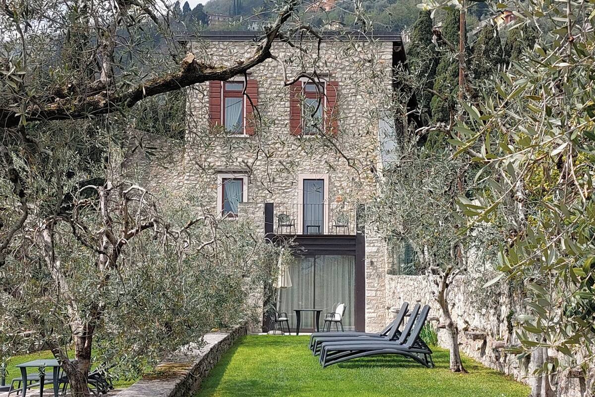 Un bâtiment en pierre doté d’un balcon, avec une petite table et des chaises au premier plan.