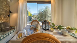 Ein gemütliches Zimmer mit Frühstückstisch, einer Couch und Blick ins Freie.