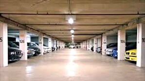 Un estacionamiento con varios niveles, columnas de hormigón y suelo reflectante.