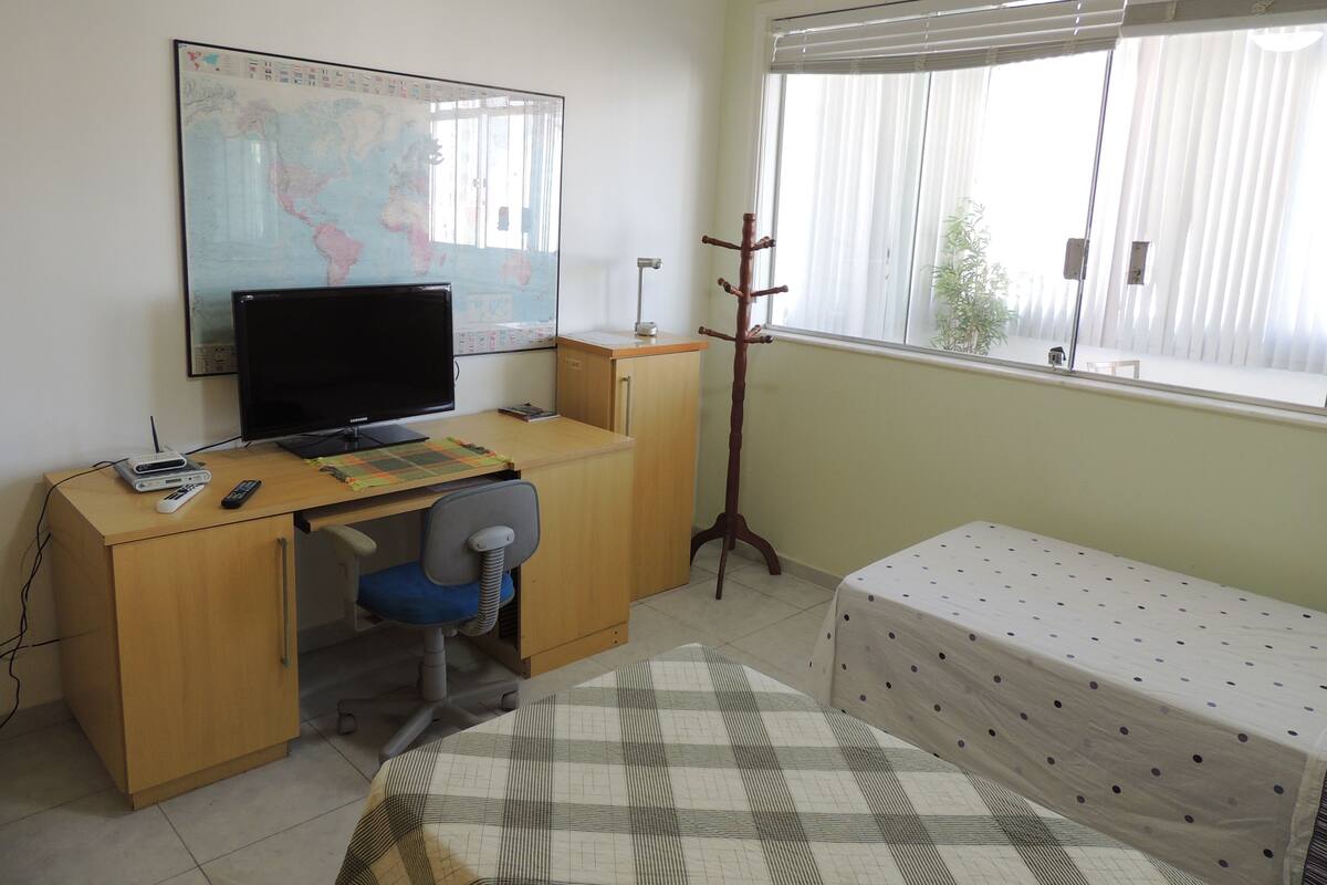 Une pièce comprenant un bureau, une chaise, un lit et une carte accrochée au mur.