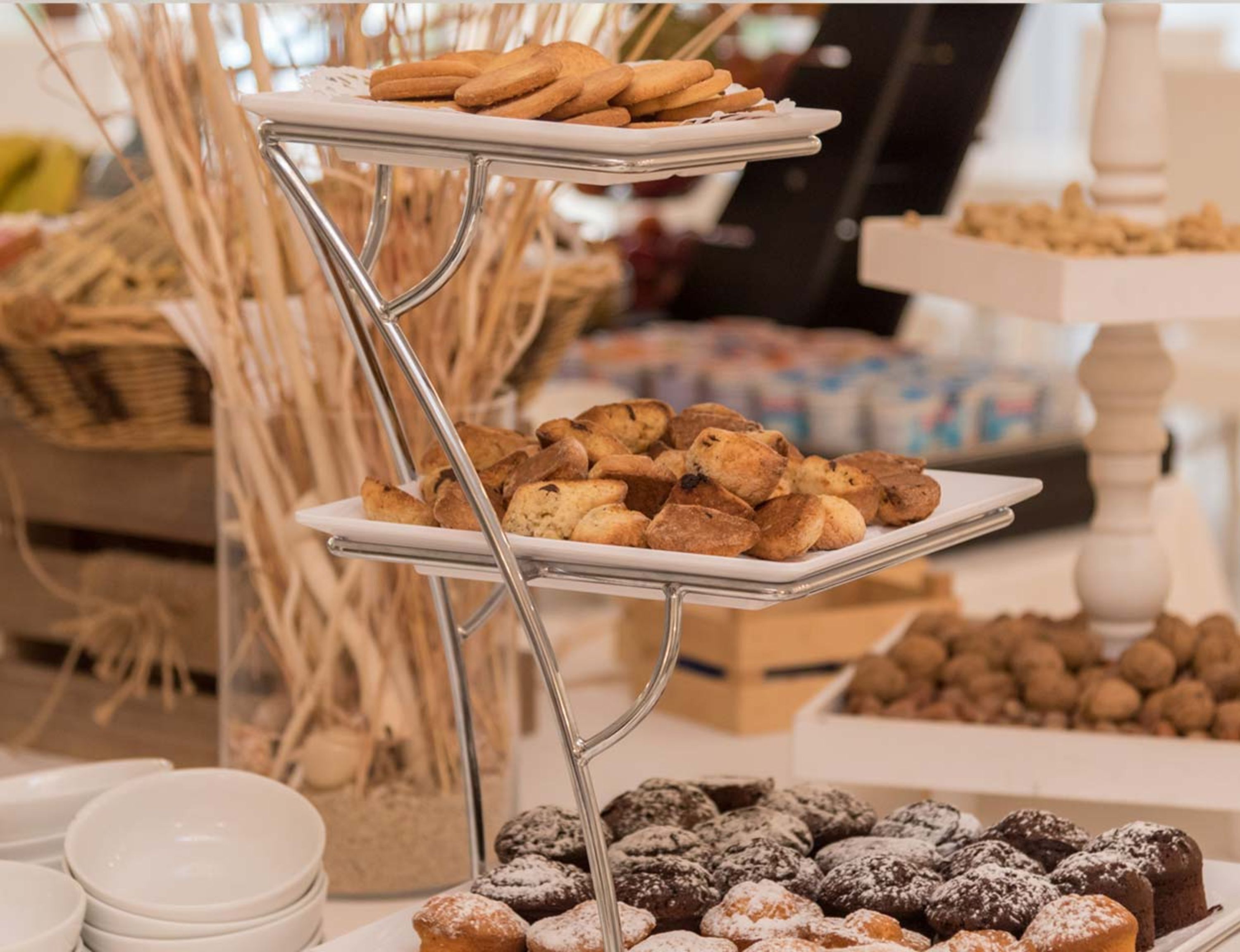 Buffet com diversos doces e sobremesas, incluindo bolachas, muffins e doces polvilhados.