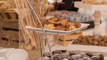 Buffet com diversos doces e sobremesas, incluindo bolachas, muffins e doces polvilhados.
