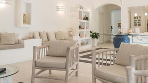A modern living room with a sofa, two armchairs, a glass coffee table, and a chandelier. - Hotel Residence Il Porto (Mattinata)