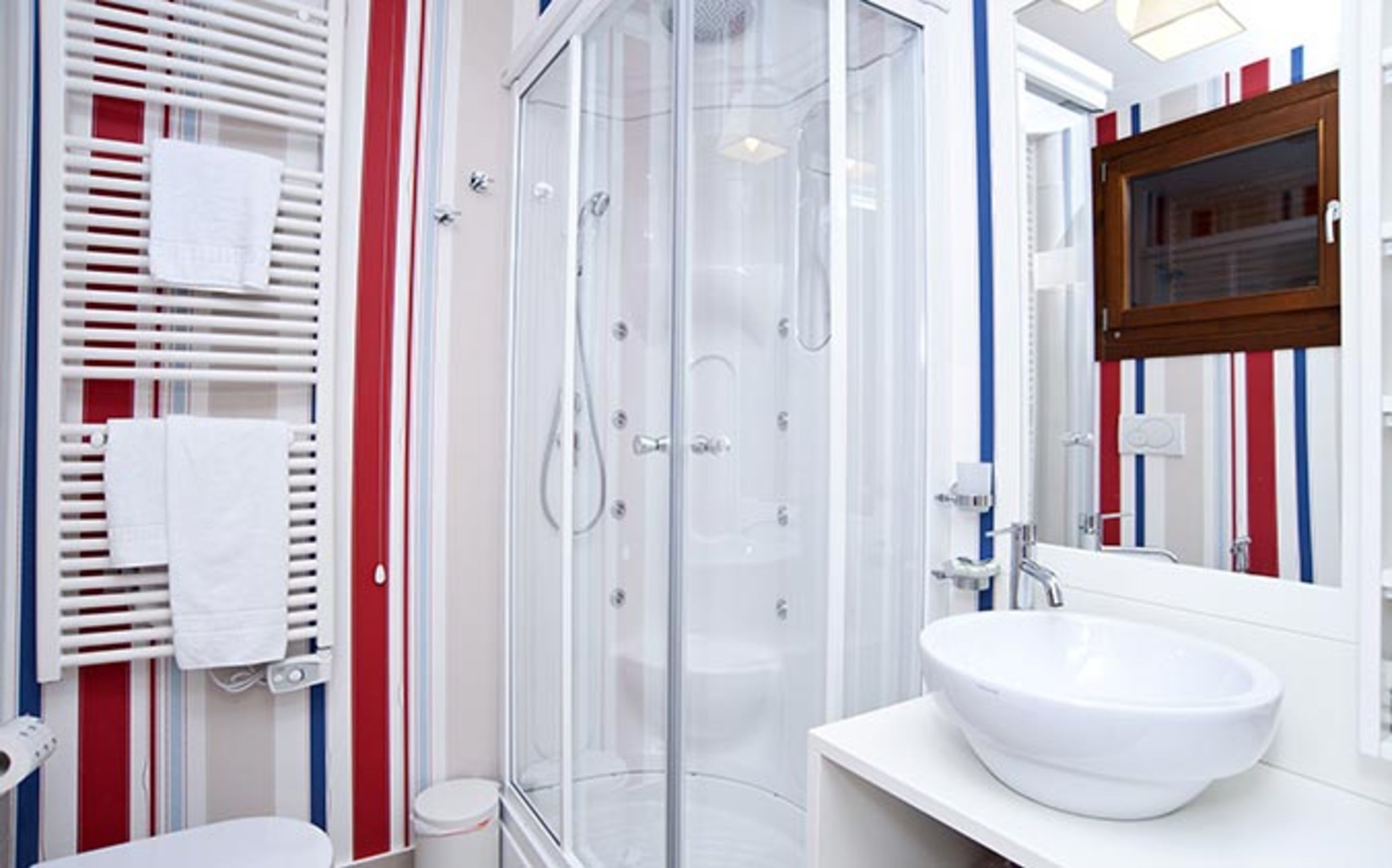 Casa de banho moderna com cabine de duche em vidro, lavatório branco e espelho com moldura de madeira.