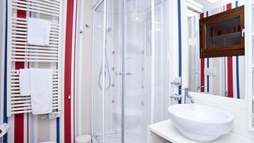 A modern bathroom with a glass shower enclosure, a white sink, and a mirror with a wooden frame.
