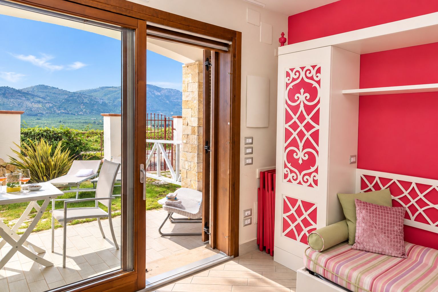 Ein Zimmer mit Bergblick, ein Balkon mit Tisch und Stühlen sowie ein Bett mit Kissen.