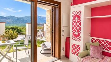 Ein Zimmer mit Bergblick, ein Balkon mit Tisch und Stühlen sowie ein Bett mit Kissen.