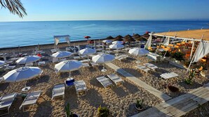 A beach with sun loungers, umbrellas, and a wooden deck. - Hotel Residence Il Porto (Mattinata)