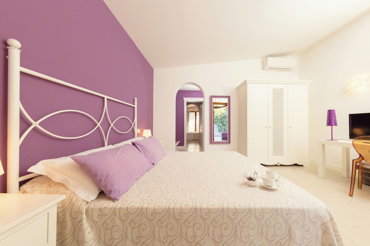 Ein Schlafzimmer mit Bett, Kleiderschrank, Schreibtisch und Fernseher.