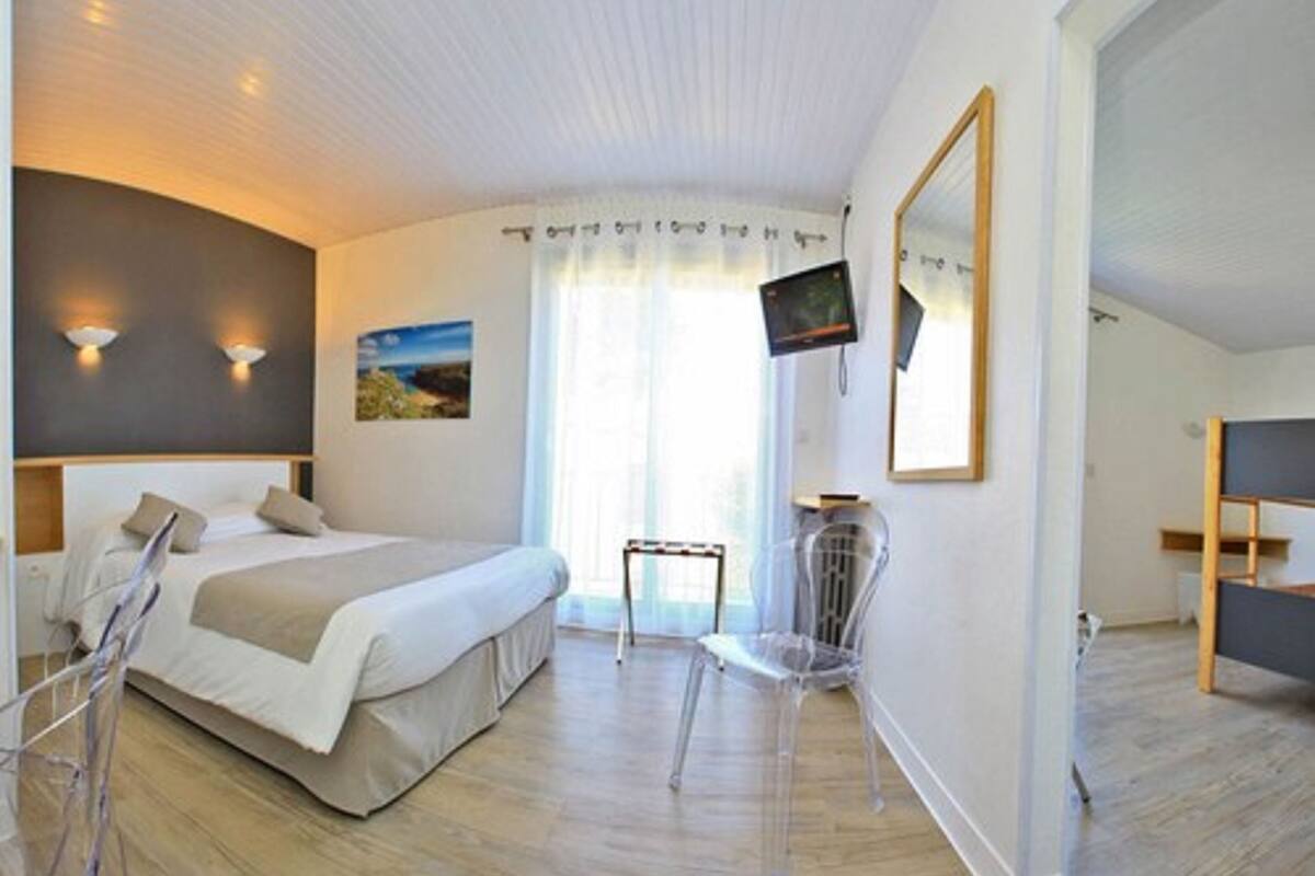Une chambre d’hôtel moderne avec un grand lit, un téléviseur fixé au mur et une chaise transparente.