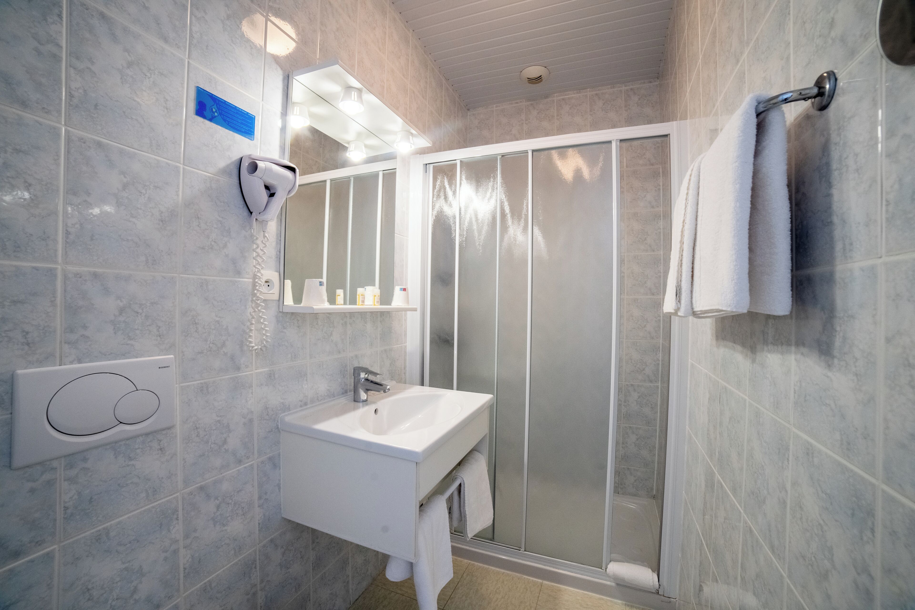 A modern bathroom with a white sink, a glass shower enclosure, and a towel rack.