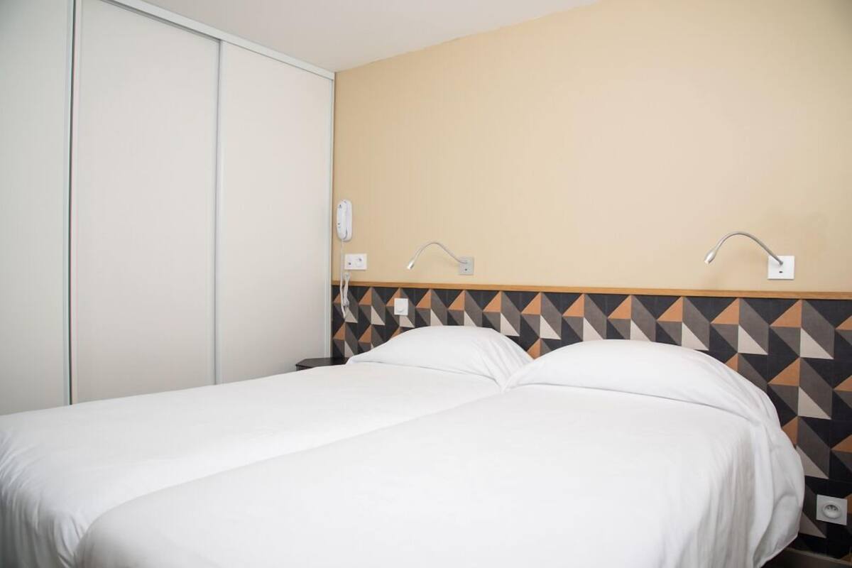 Une chambre d’hôtel avec un lit, une armoire et un mur orné d’un motif géométrique.