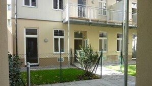 Une cour avec un chemin pavé, une petite pelouse et une clôture en métal.