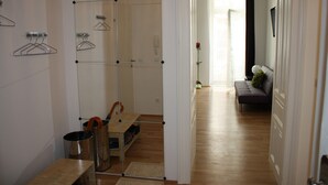 Un couloir avec un miroir, un banc et un coin salon comprenant un canapé et une plante en pot.