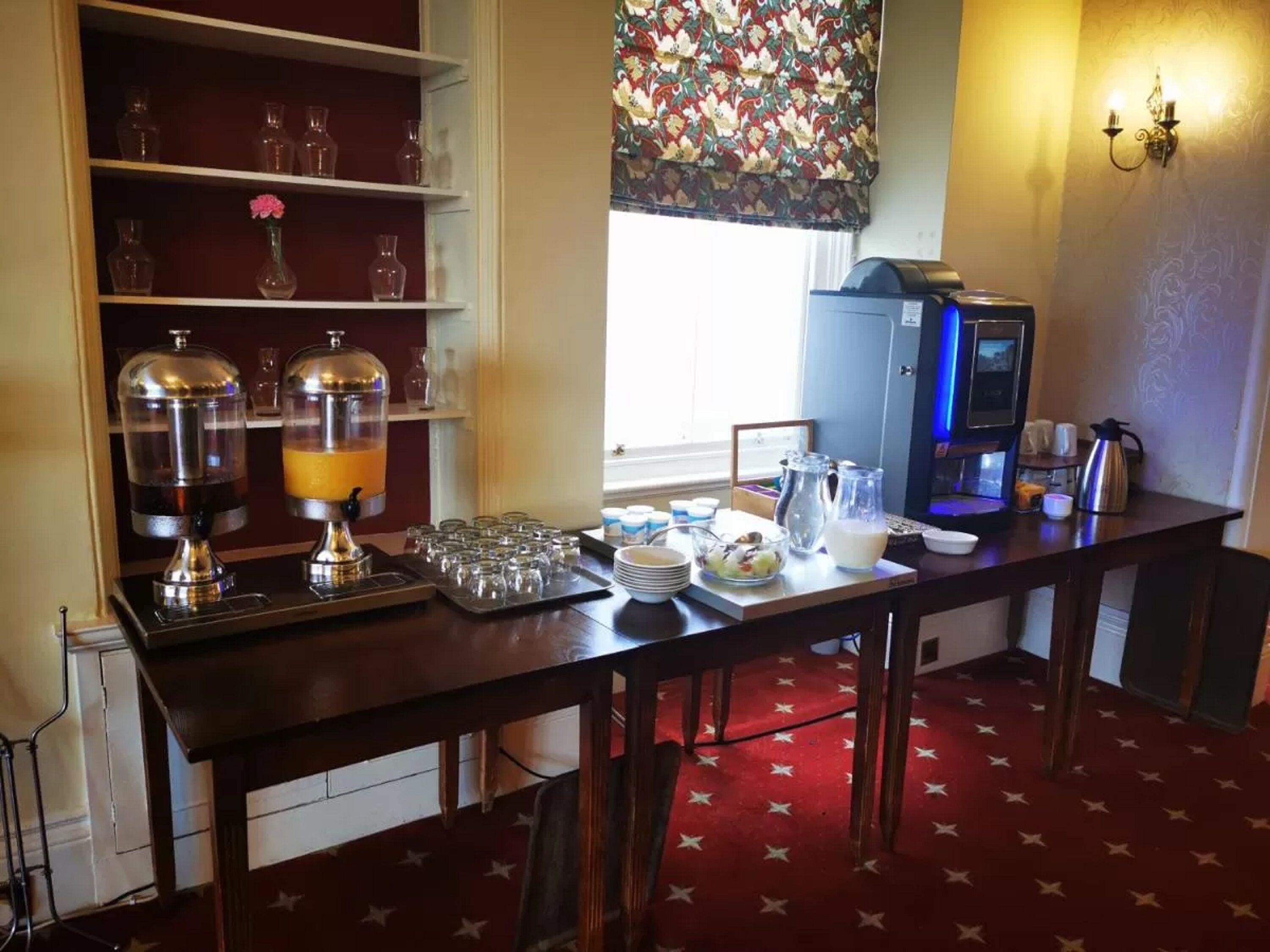 Ein Frühstücksbuffet mit Kaffeeautomat, Saftspendern und verschiedenen Frühstücksangeboten.