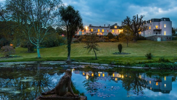 A pond with a statue, surrounded by a well-maintained lawn and trees, with a building in the background. - The Cliffden Hotel (Teignmouth)