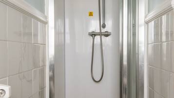 A walk-in shower with a glass door, a handheld showerhead, and a handheld hose.