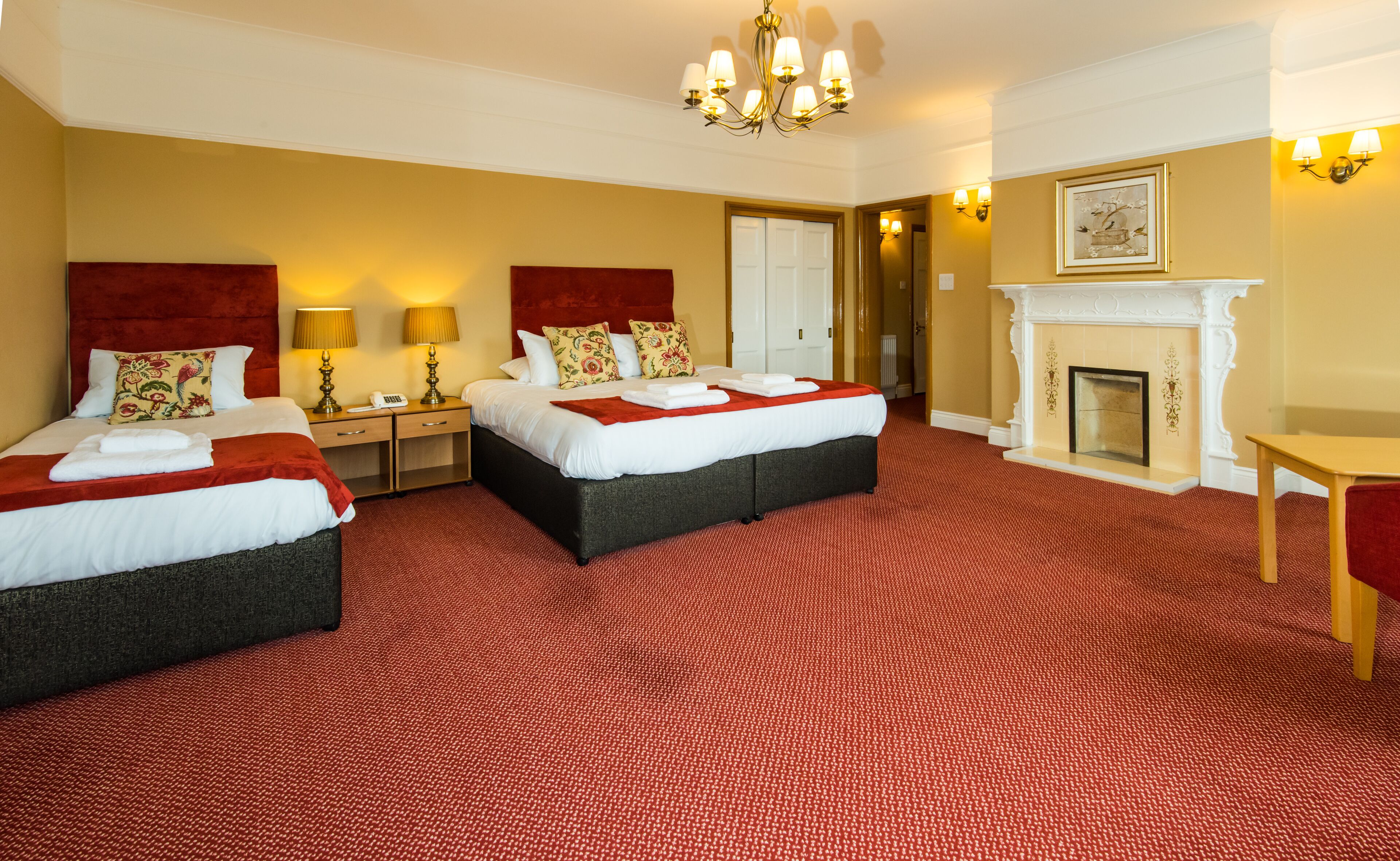 Ein Hotelzimmer mit zwei Betten, einem Kamin und einer Chandelier.