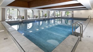 A large indoor swimming pool with clear blue water, surrounded by seating areas and large windows. - The Cliffden Hotel (Teignmouth)