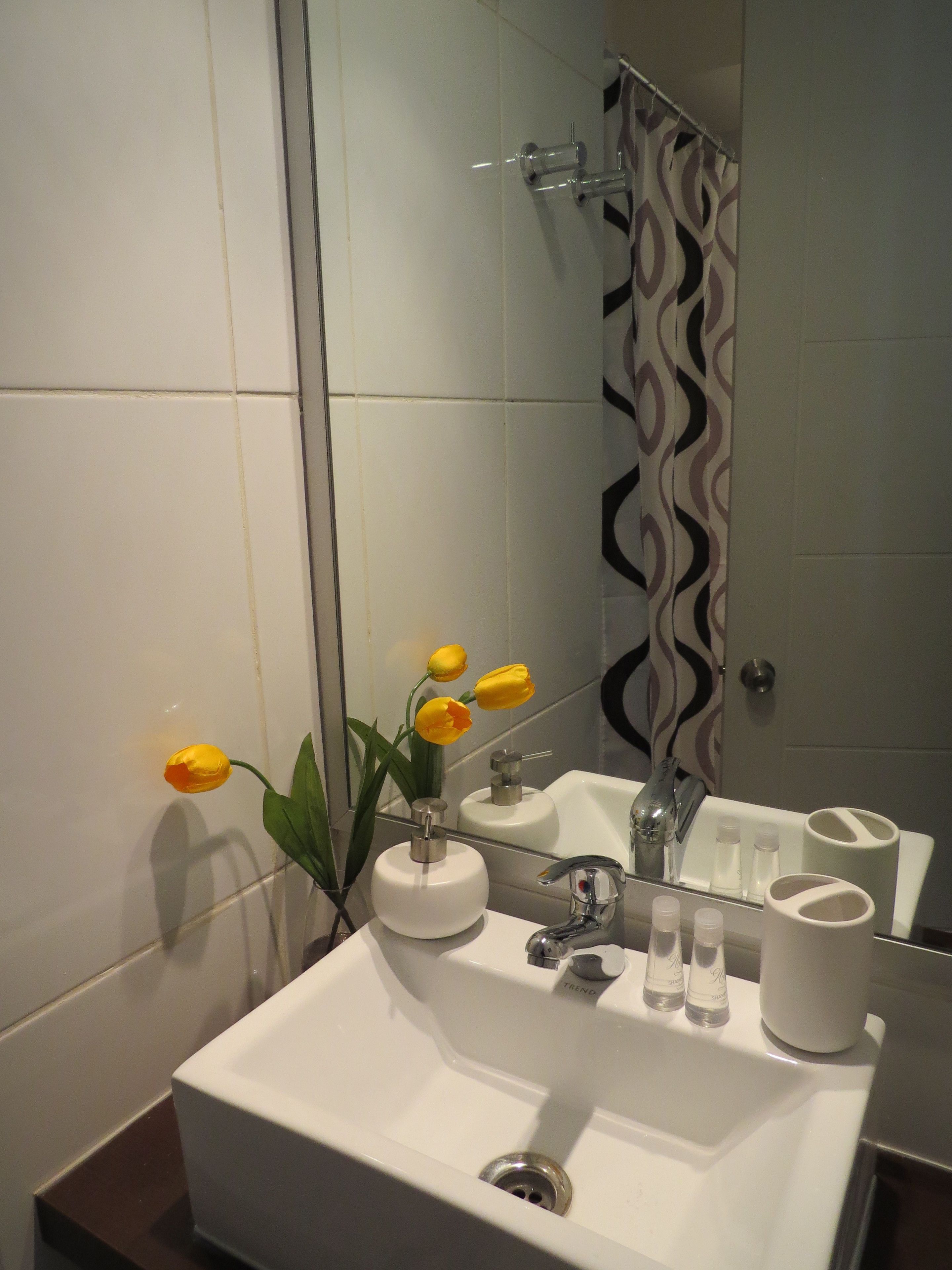 A bathroom with a white sink, mirror, and shower curtain.