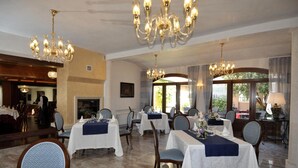Comedor con varias mesas, candelabros y vistas al exterior.