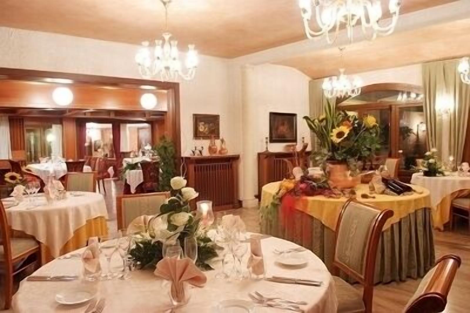 Ein Essbereich mit runden Tischen, gedeckt für eine Mahlzeit, jeweils mit Tischdekoration und Kerzen.
