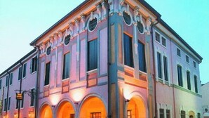 Un edificio histórico con fachada simétrica, ventanas arqueadas y una entrada central.