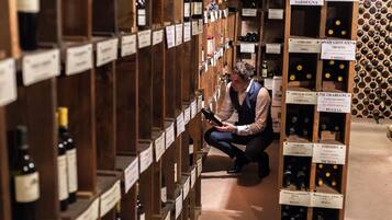 A wine cellar with wooden shelves and labels indicating different wine varieties.