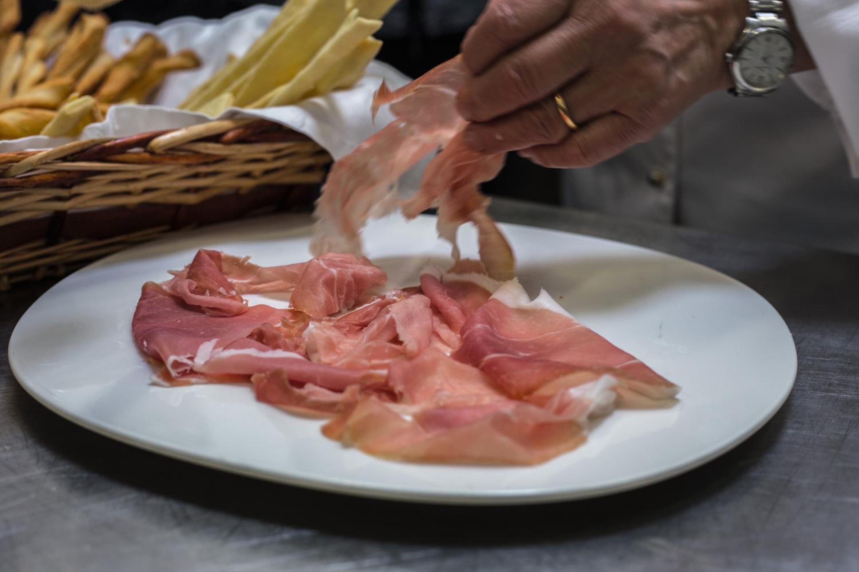 A plate of thinly sliced cured meat on a white plate.