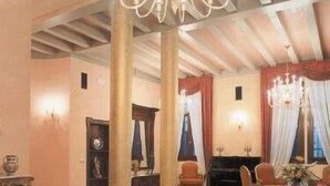 Una habitación amplia con techo alto, una araña y un piano.