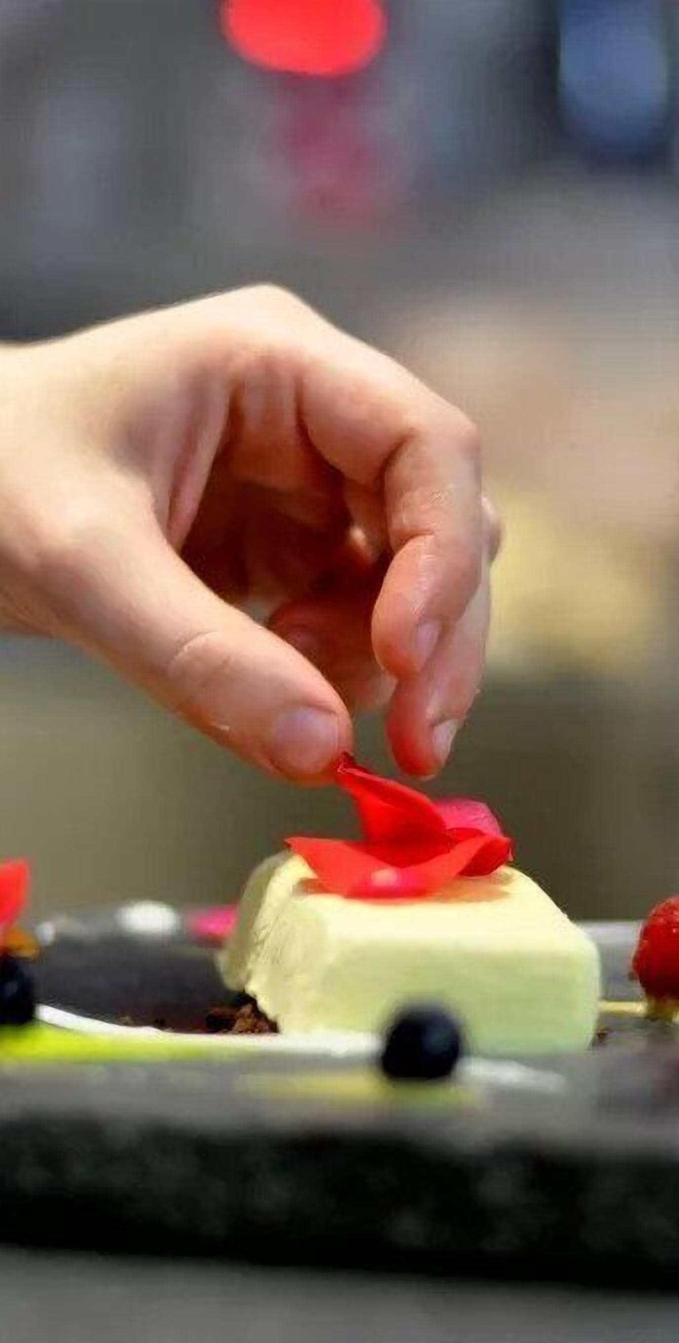 Eine Hand legt ein rotes Band auf ein Dessert.
