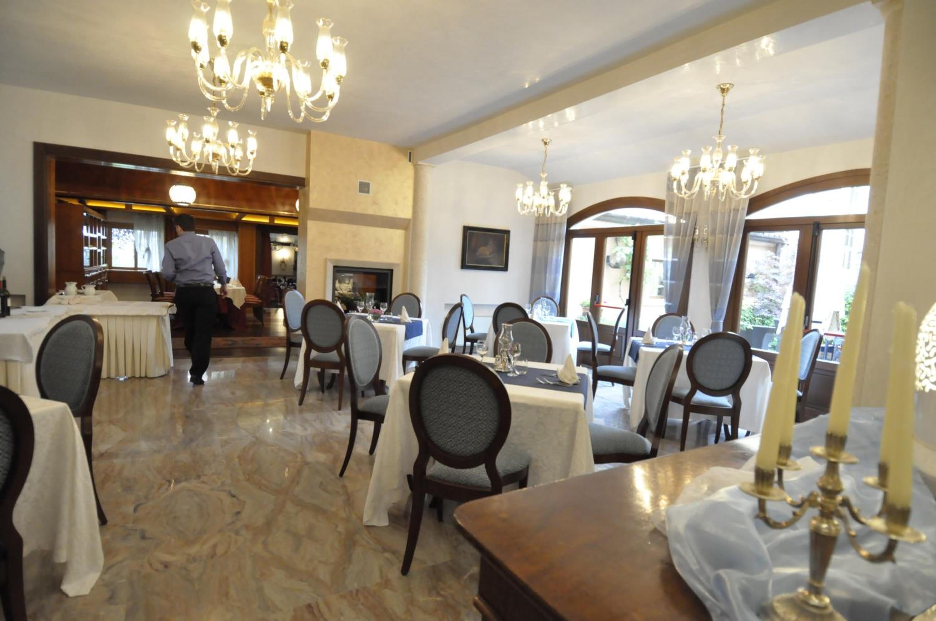 Un amplio comedor con varias mesas y sillas, candelabros y vistas al exterior.