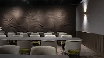 A conference room with a long table and chairs, a textured wall, and a wall-mounted light fixture.
