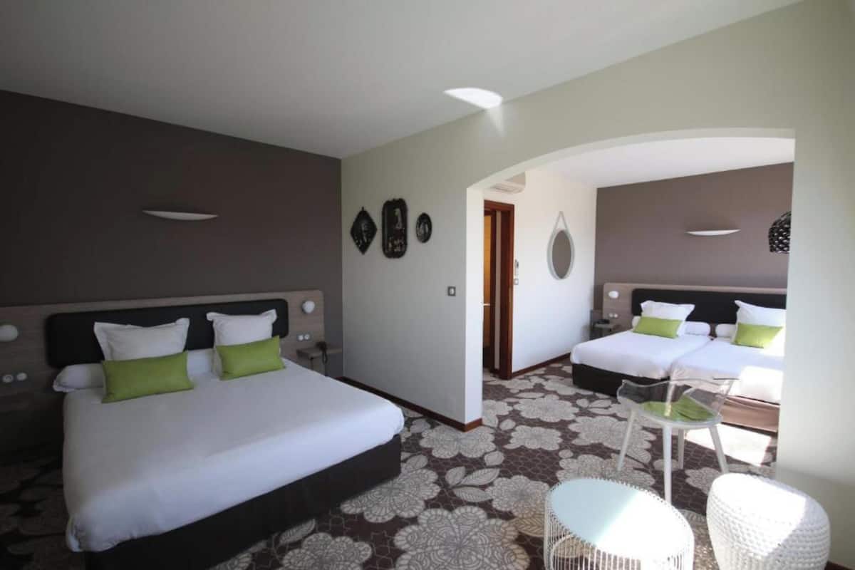 Een hotelkamer met twee bedden, een zithoek met een stoel en een kleine tafel.