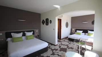 Habitación de hotel con dos camas, una zona de estar con una silla y una mesita.