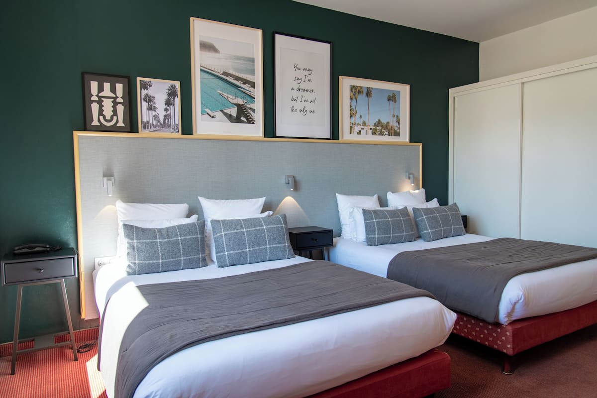 Een hotelkamer met twee bedden, een nachtkastje en een kledingkast.