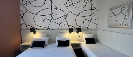 A hotel room with a large bed, two bedside tables, and a wall with abstract art.