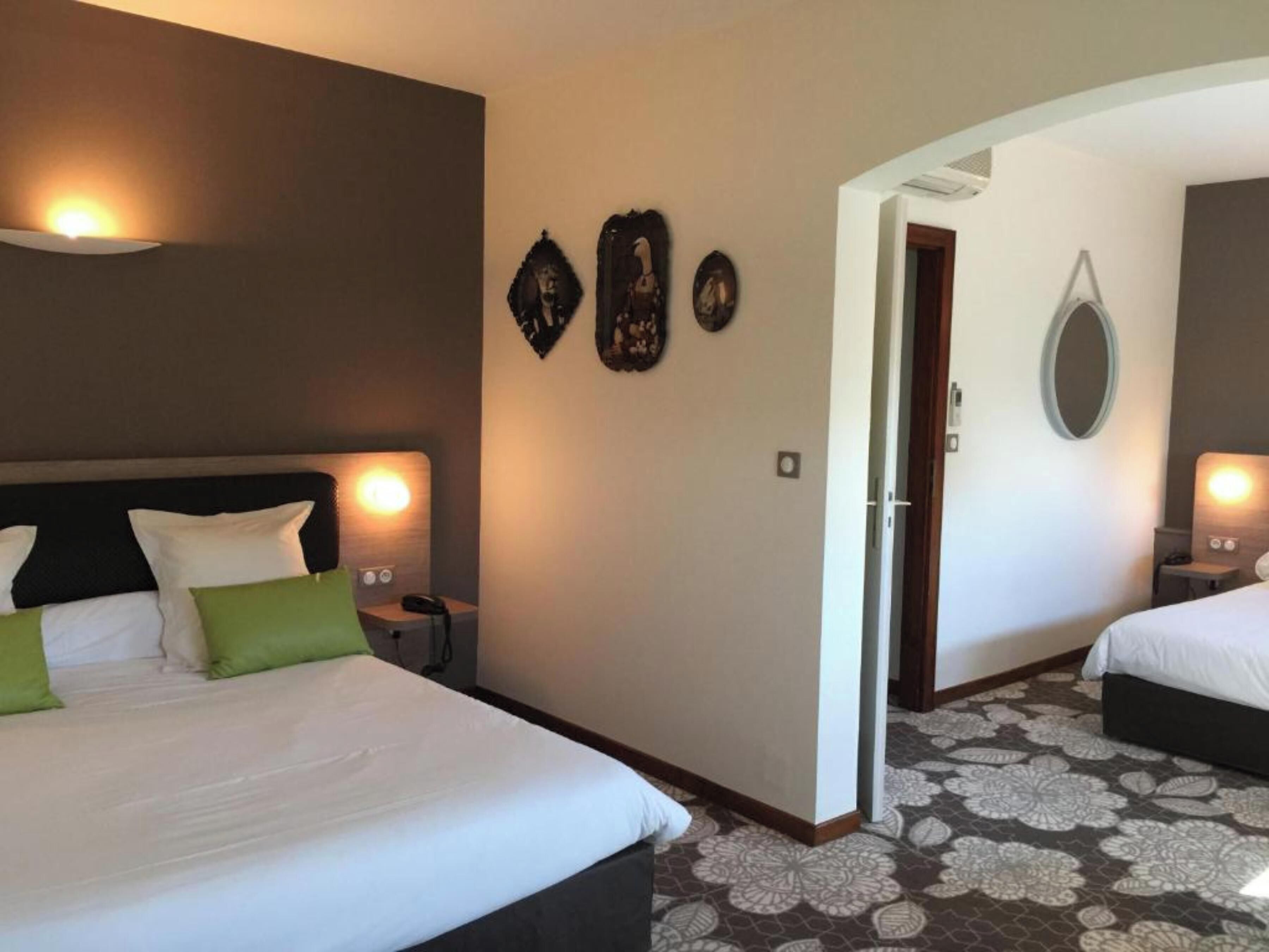 A hotel room with two beds, a large mirror, and decorative wall art.