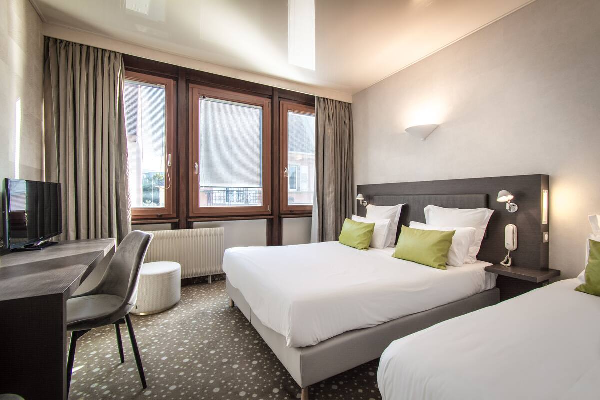 Een hotelkamer met twee bedden, een bureau, een stoel en een televisie.