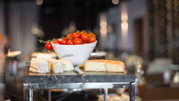 Een buffettafel met verschillende kazen en een schaal kers tomaten.