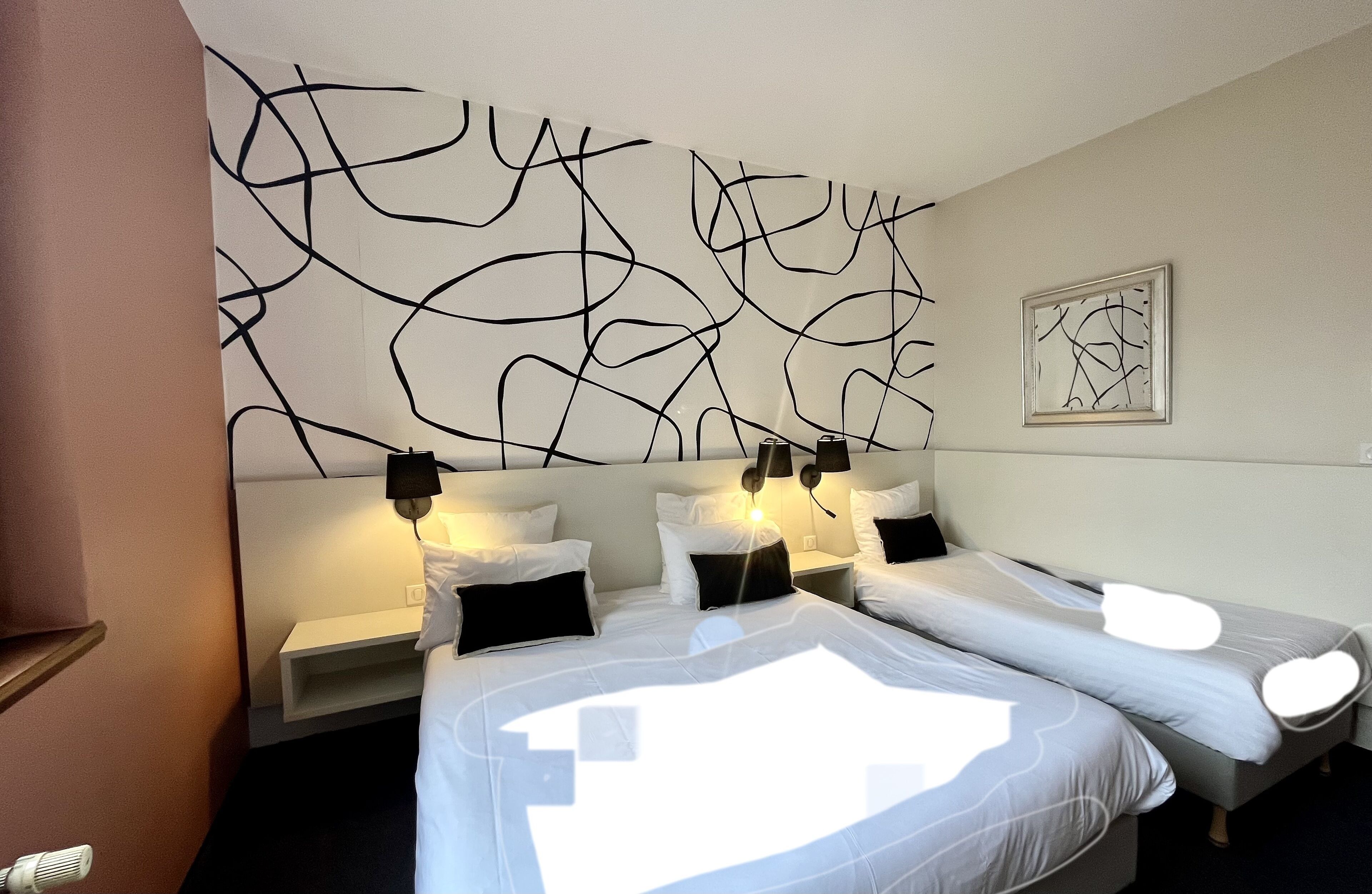 A hotel room with two beds, a modern abstract wall art, and a framed picture on the wall.