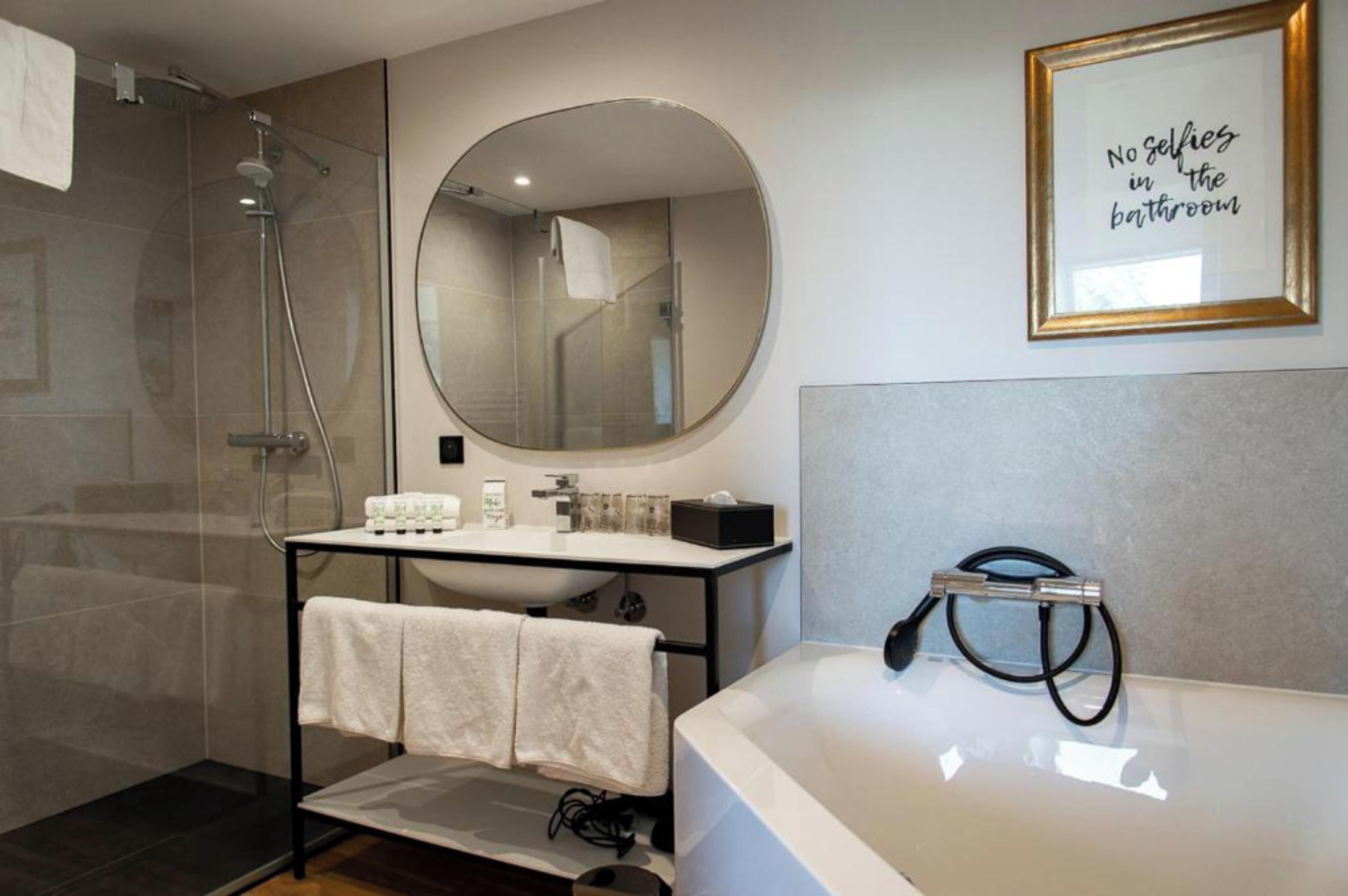Une salle de bain moderne avec un grand miroir, une baignoire et une douche.