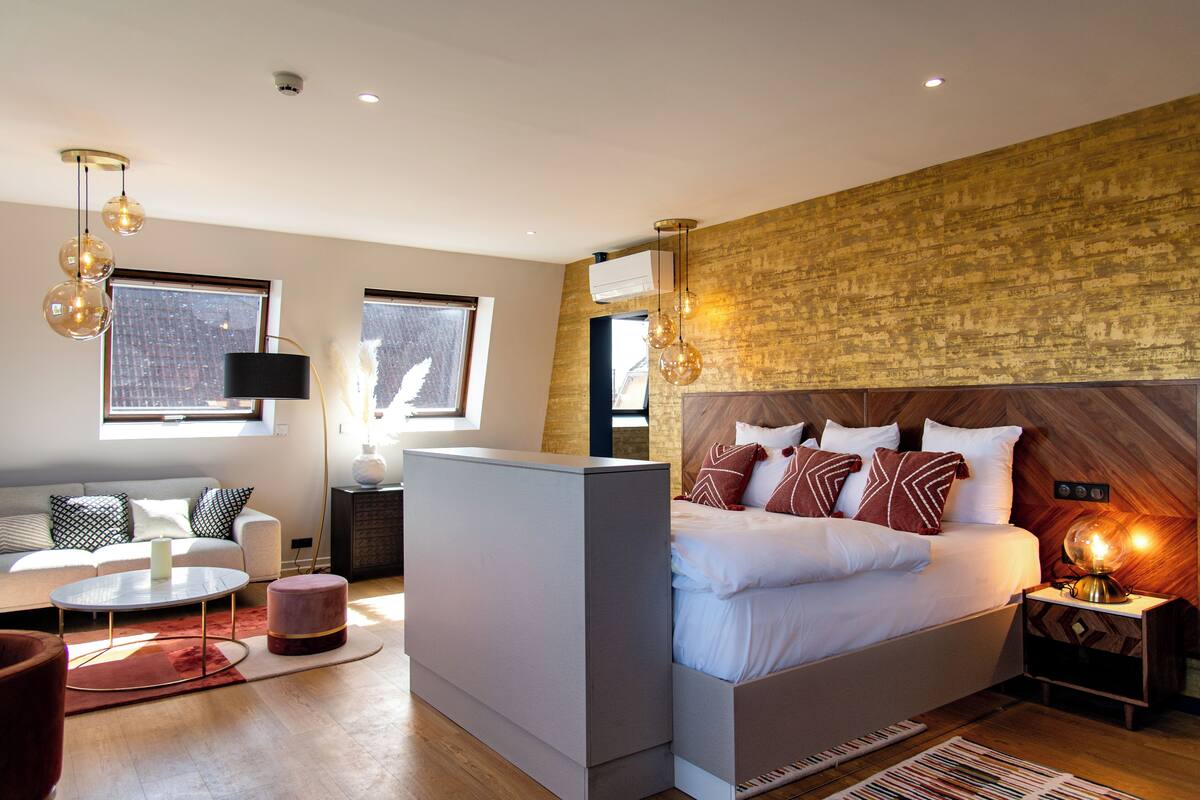 Een moderne slaapkamer met een groot bed, een bank, een ronde salontafel en een klein vloerkleed.