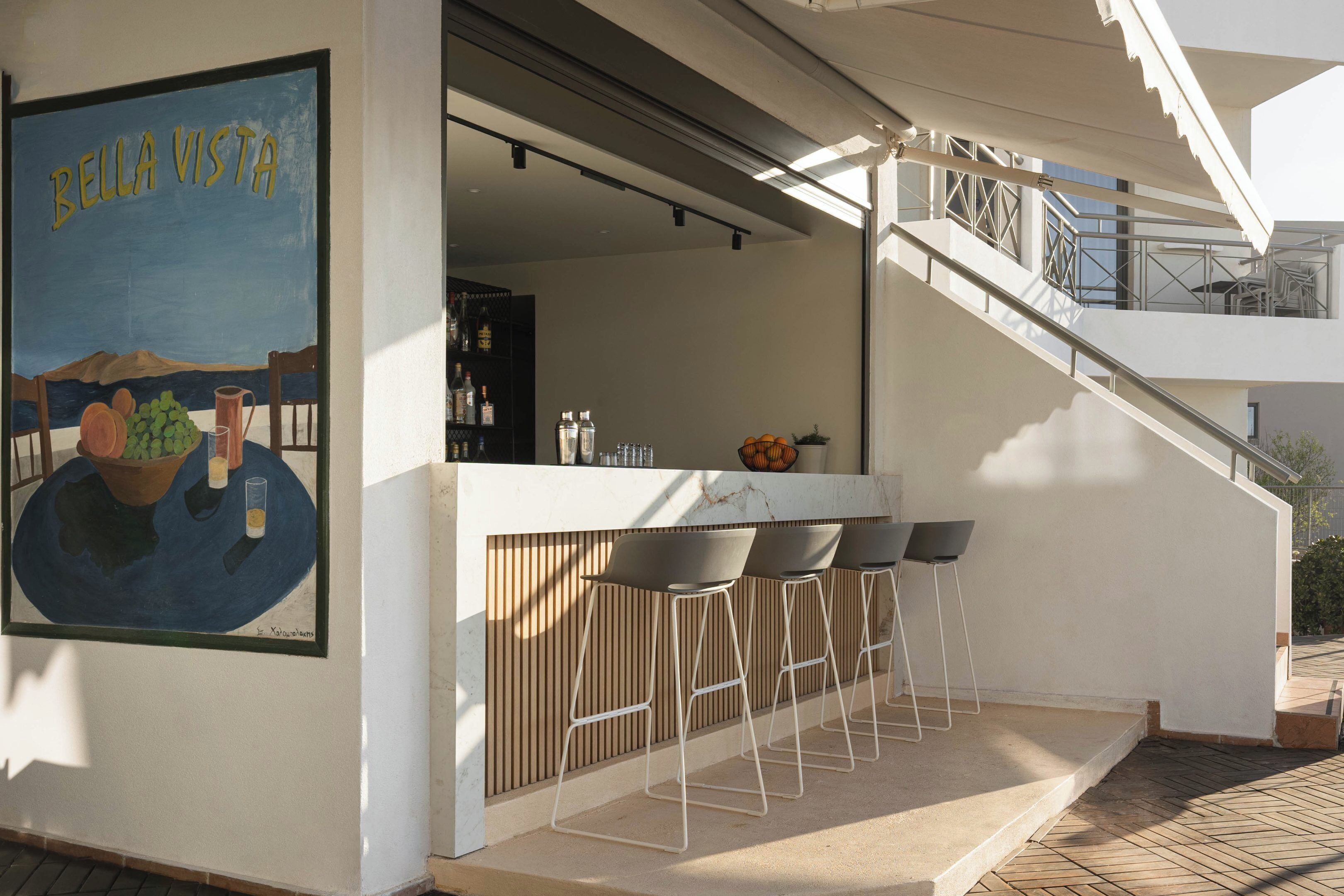 A bar area with a mural, bar stools, and a staircase leading to an upper level.