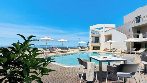 A poolside area with lounge chairs, umbrellas, and a table. - Bella Vista Hotel by Checkin (Hersonissos)