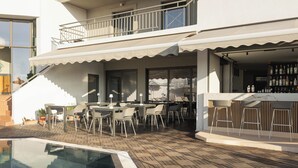 A poolside area with outdoor seating, a bar, and a staircase leading to a balcony. - Bella Vista Hotel by Checkin (Hersonissos)