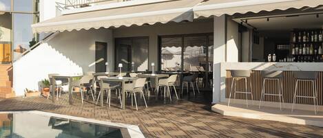 A poolside area with outdoor seating, a bar, and a staircase leading to a balcony.