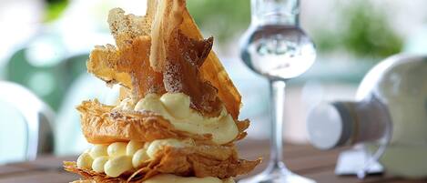 A dessert on a plate with a glass of water and a bottle in the background.