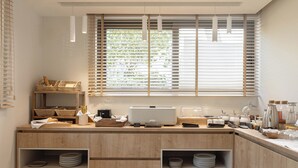 A modern kitchen with wooden cabinets, a built-in bread basket, and a coffee station. - Bella Vista Hotel by Checkin (Hersonissos)